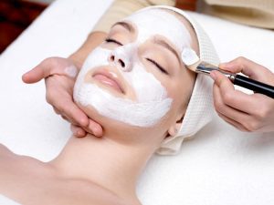 Best Facials in Loudoun County | Beautiful young woman receiving facial mask at beauty salon.